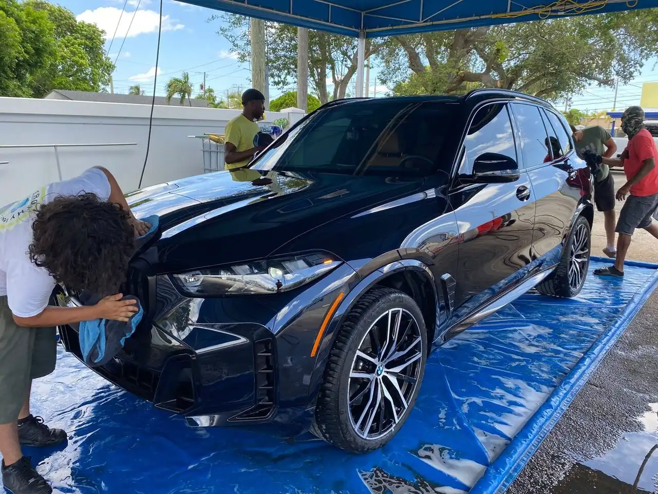 Black BMW X7 covered in foam with our team washing