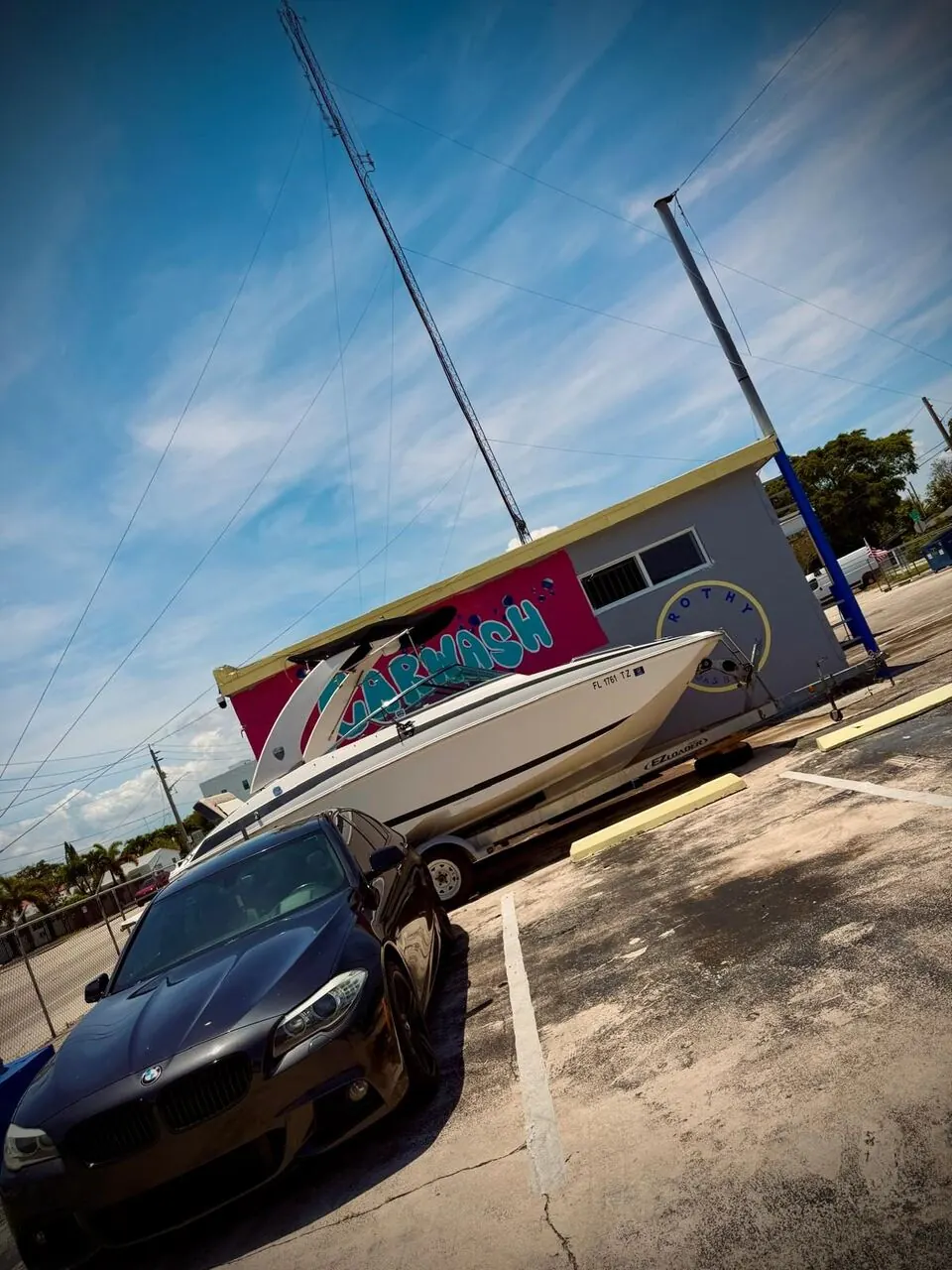 Boat and black car parked at Frothy Carwash
